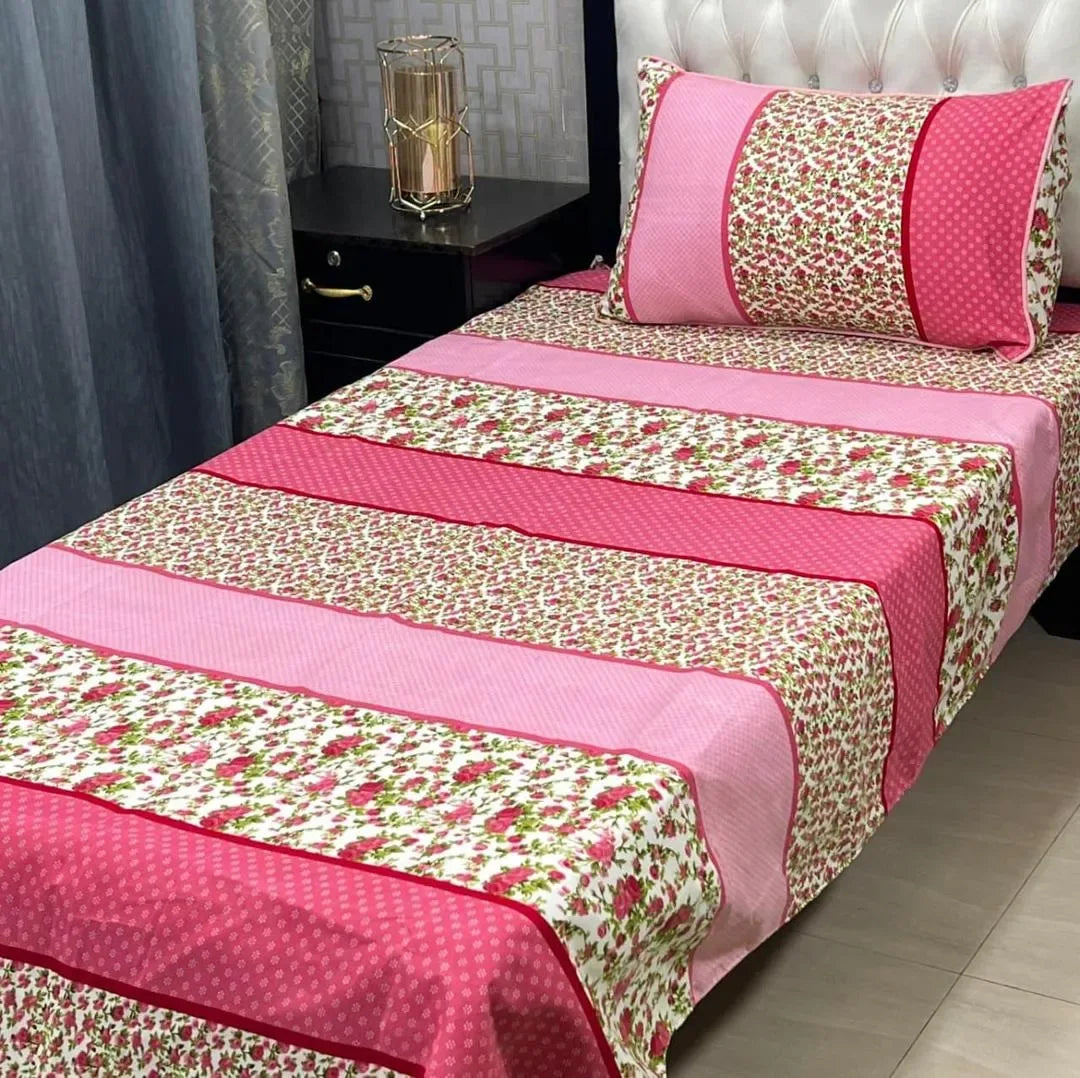 Bed with floral and pink patterned bedding in a bedroom setting.