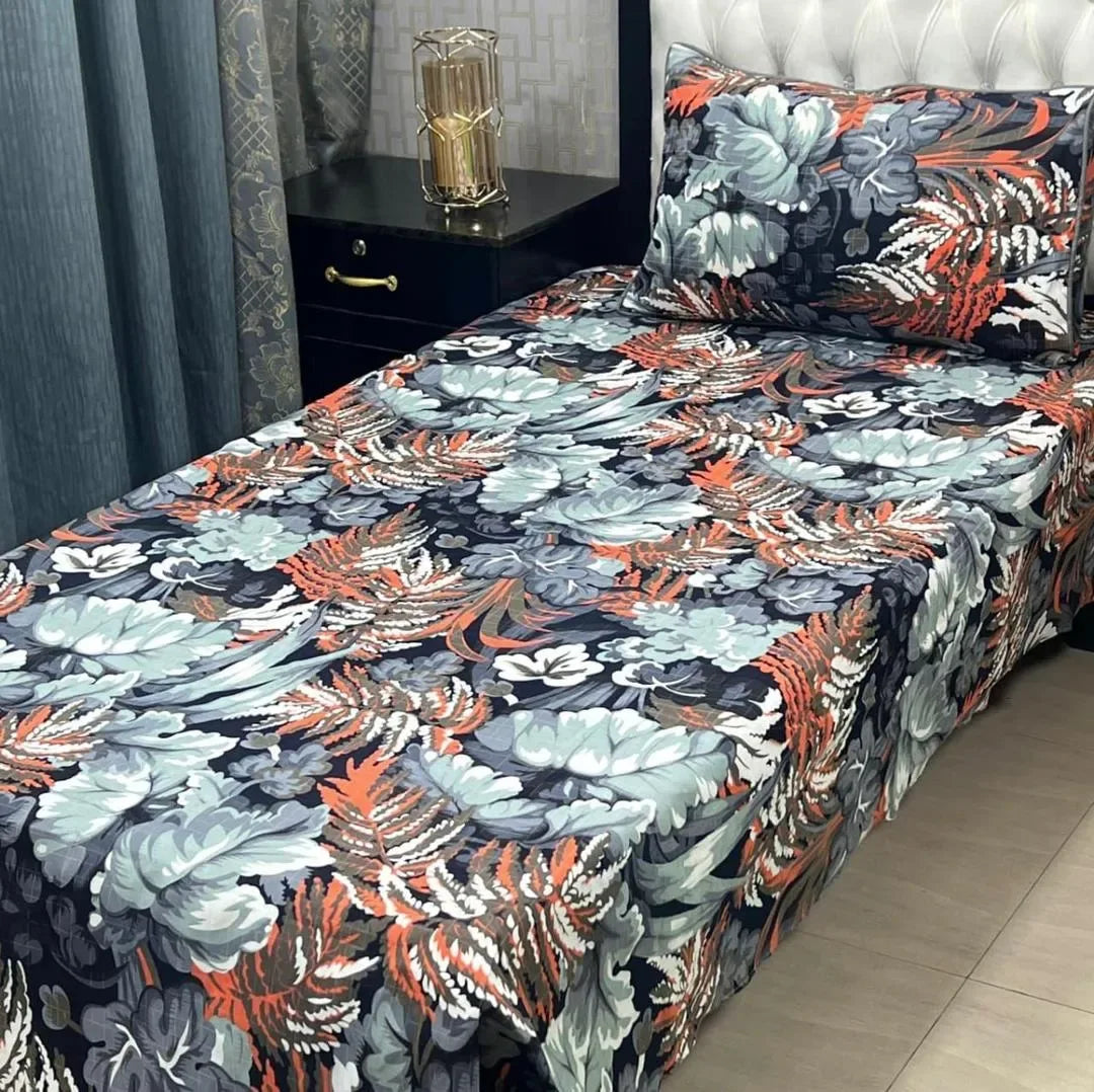 Floral patterned bedspread on a bed with a nightstand in the background.