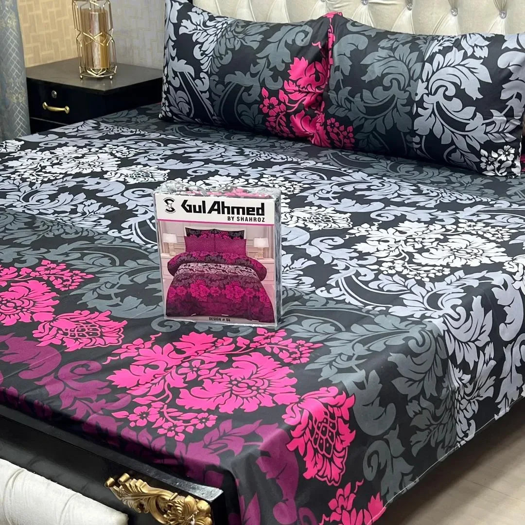 Bedspread with pink floral patterns on a bed, featuring a Gul Ahmed product packaging.