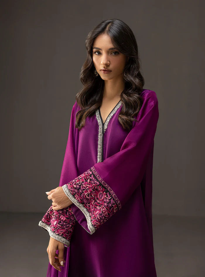 Woman wearing a purple dress with intricate patterns on a dark background