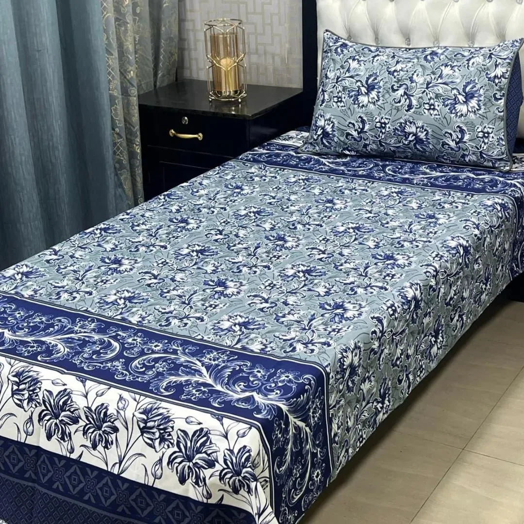 Bed with blue and white floral patterned bedding in a bedroom setting.