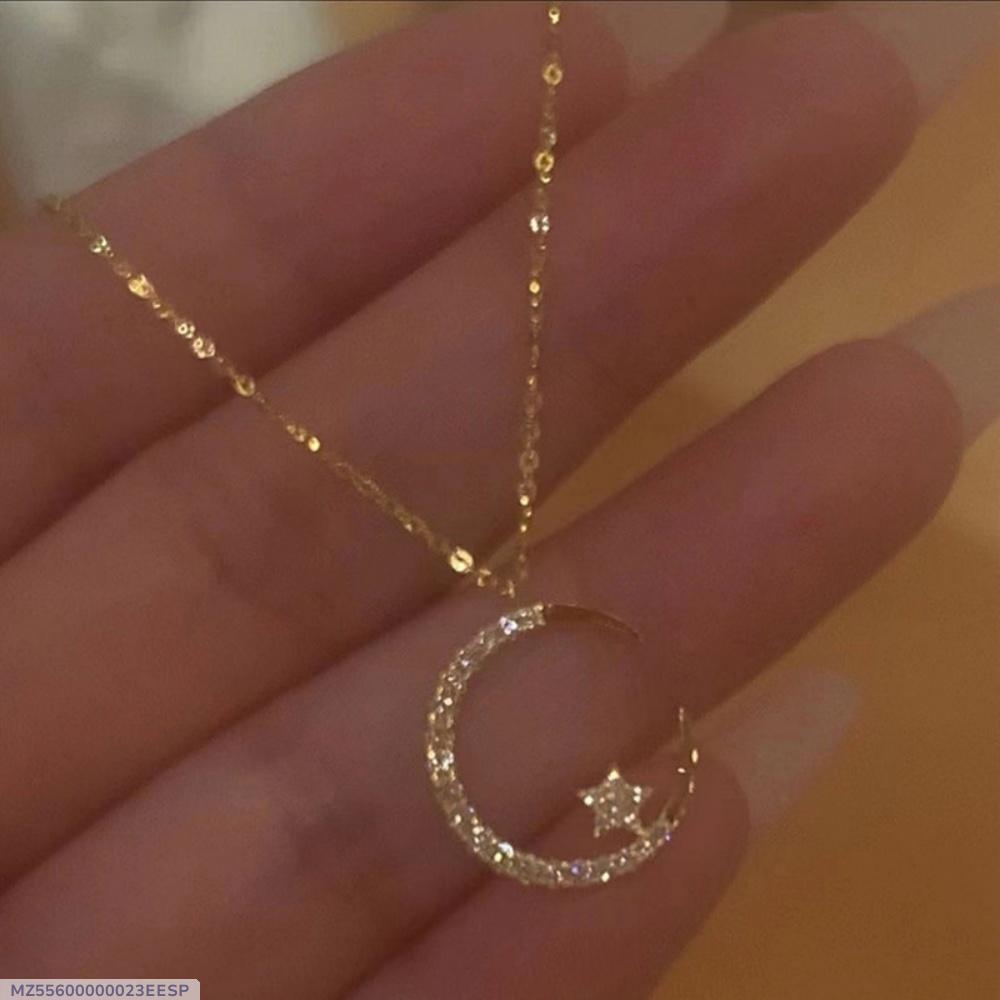 Gold necklace with a crescent moon and star pendant held in hand against a blurred background