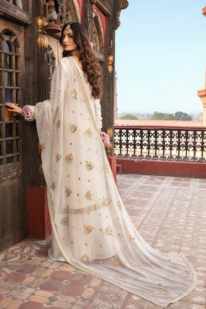 Woman in a white embroidered saree standing on a balcony with a scenic view.