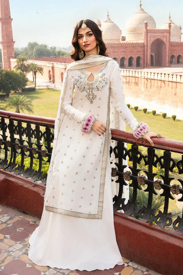 Woman in a white traditional outfit with intricate designs standing in front of a historical building.