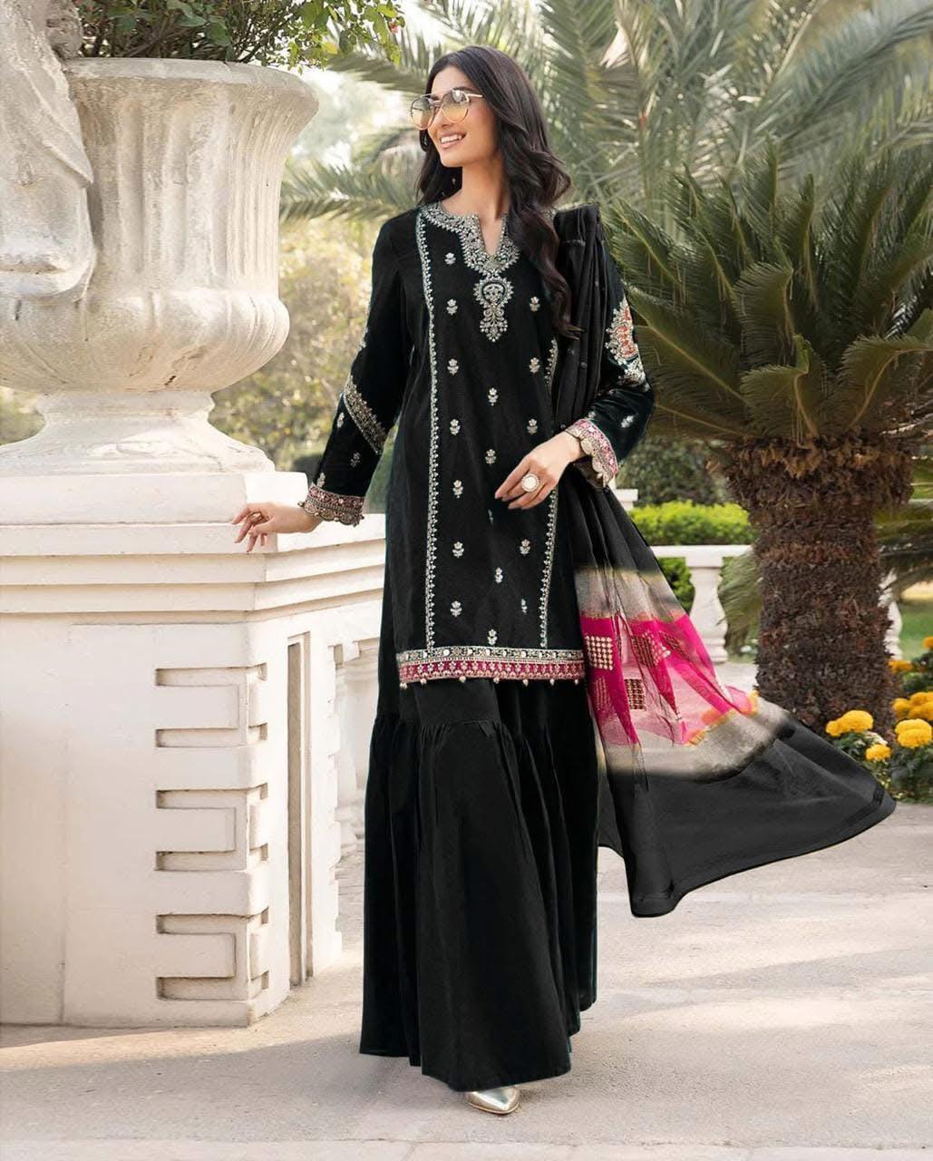 Woman in a black embroidered outfit standing outdoors with decorative elements.