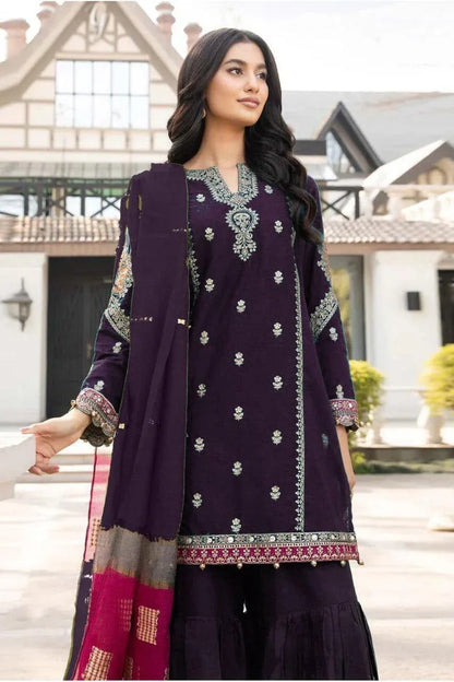 Woman wearing a dark purple traditional outfit with intricate patterns in an outdoor setting.
