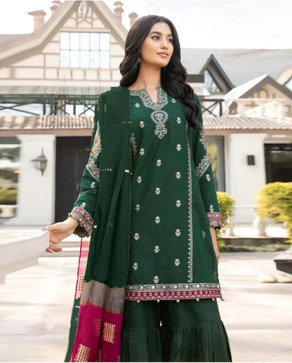 Woman in a green embroidered outfit standing in front of a building.