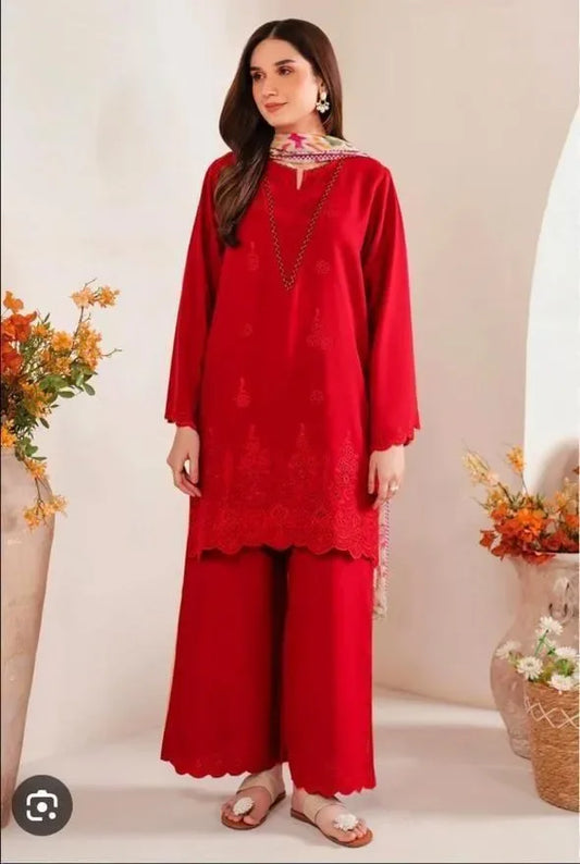 Woman wearing a red traditional outfit with floral patterns in a decorated room.