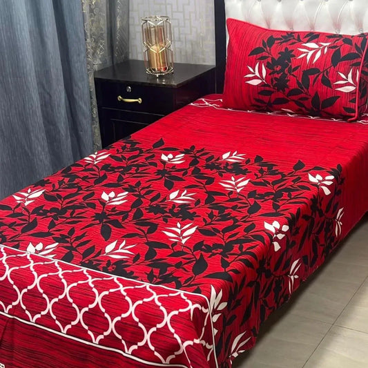 Red floral patterned bedspread on a bed with matching pillows in a bedroom setting.