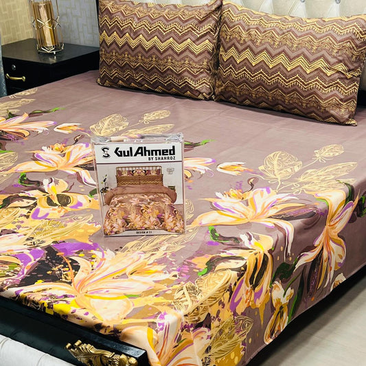 Floral patterned bedspread with a Gul Ahmed packaging box on a bed.