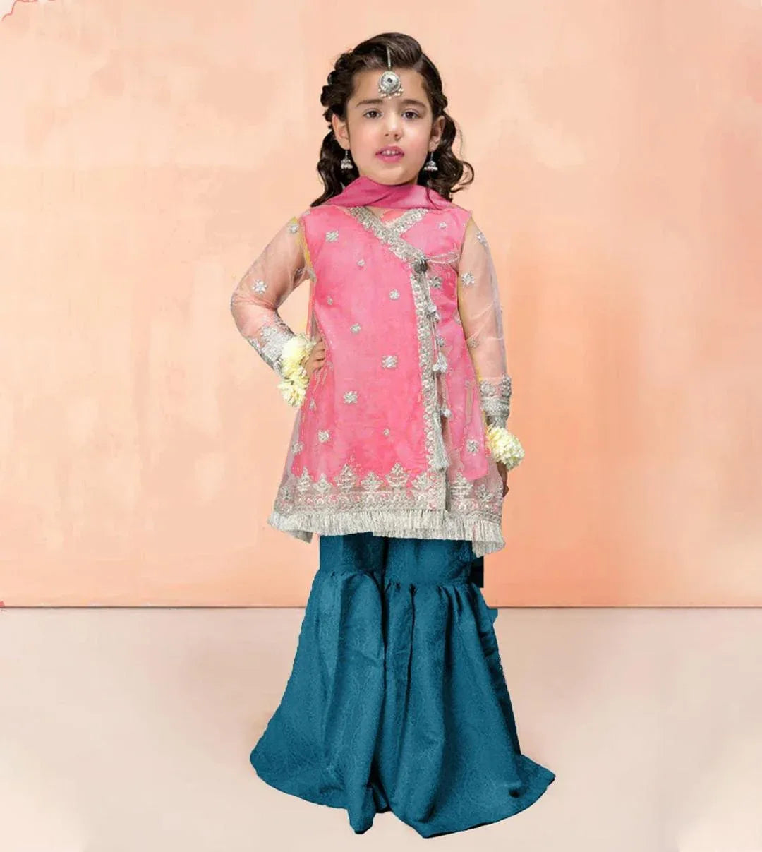 Young girl in traditional pink and blue outfit against a peach background