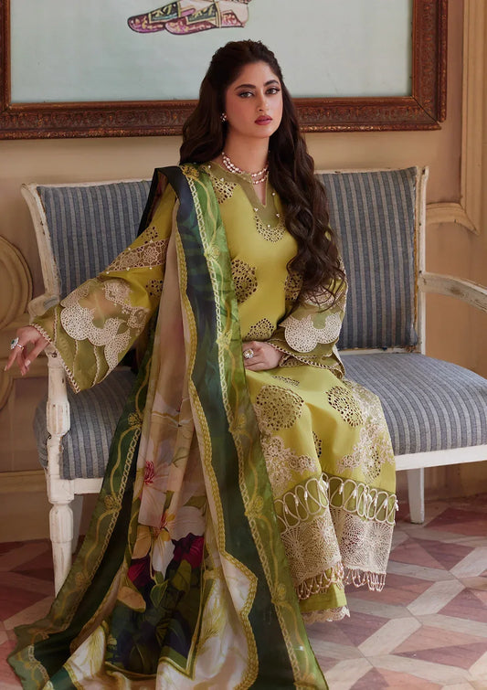 Woman in a green and gold traditional outfit sitting on a chair in an elegant room.