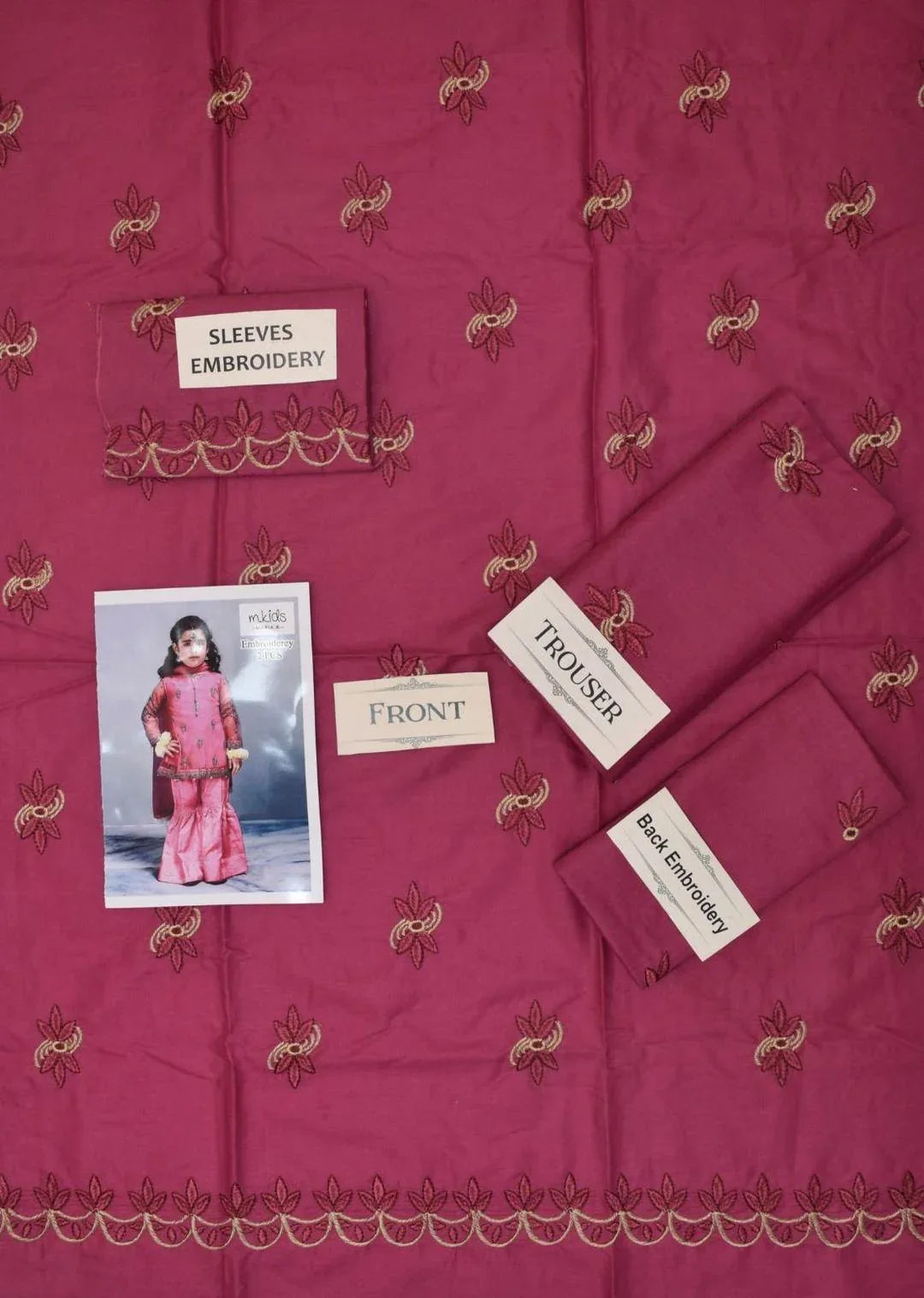Pink fabric with embroidery details and a child model wearing pink outfit on a matching fabric background.