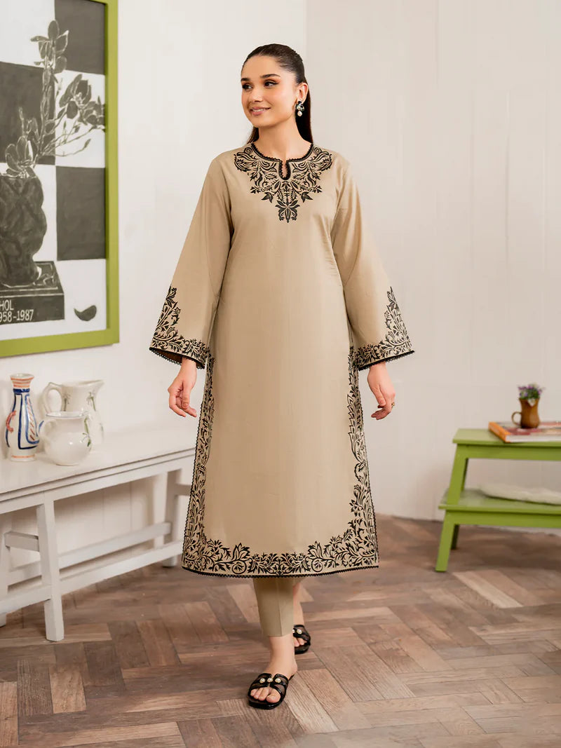 Woman wearing a beige kurta with black embroidery in a room setting.