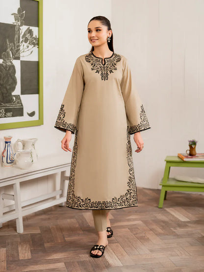 Woman wearing a beige kurta with black embroidery in a room setting.