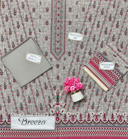 Decorative fabric with printed patterns, a small pink flower arrangement, and a gray pouch on a matching fabric background.