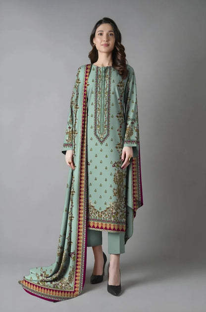 Woman wearing a light green embroidered outfit with a matching dupatta on a gray background