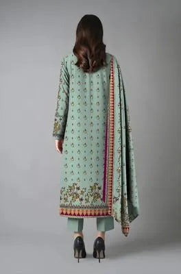 Woman wearing a light green traditional outfit with floral patterns on a gray background