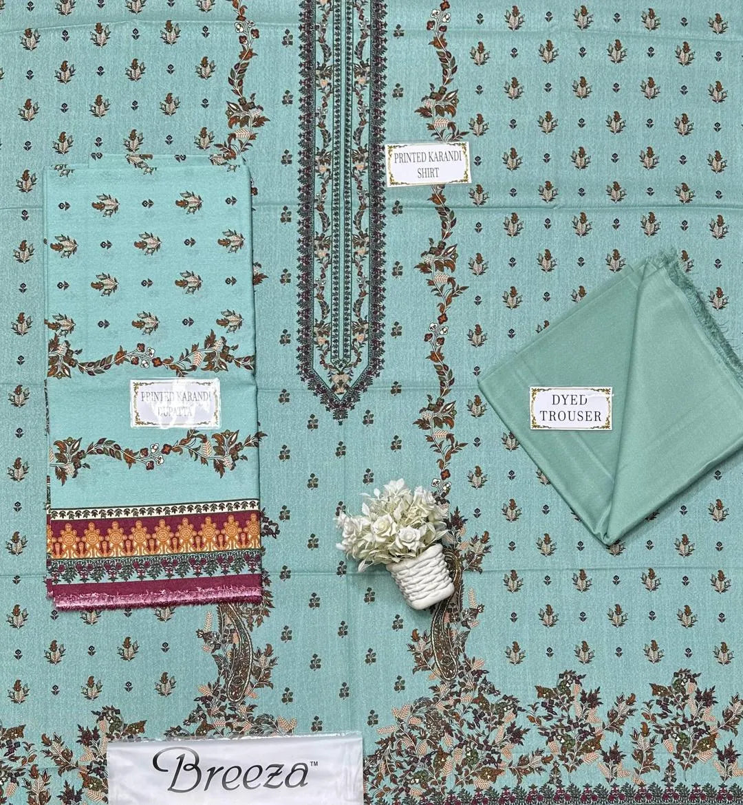 Teal fabric with intricate patterns and 'Breeza' branding, featuring a small plant and folded green fabric.