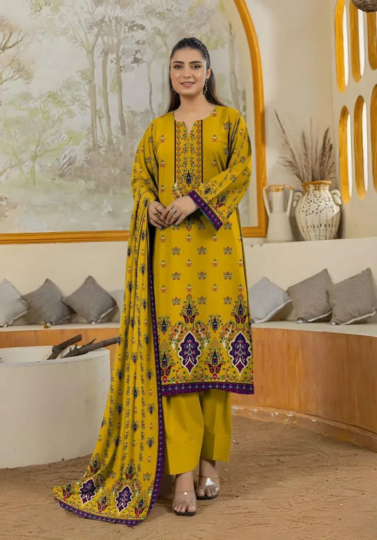 Woman in a yellow traditional outfit with purple patterns standing in a decorated room.
