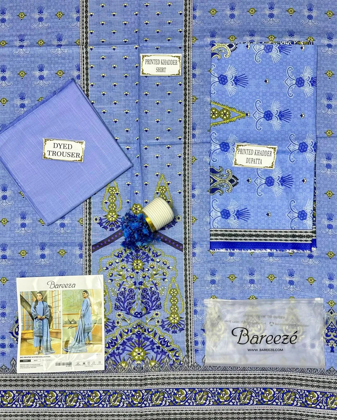 Blue fabric with intricate patterns and Bareeze branding, including a spool of thread and a label.