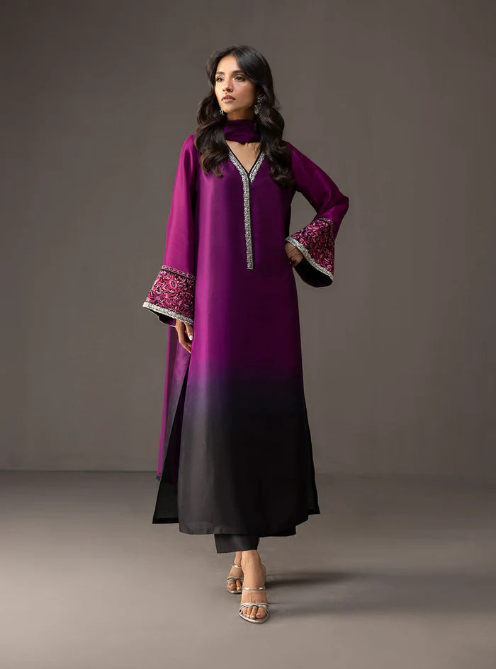 Woman wearing a purple and black dress with floral embroidery on a gray background