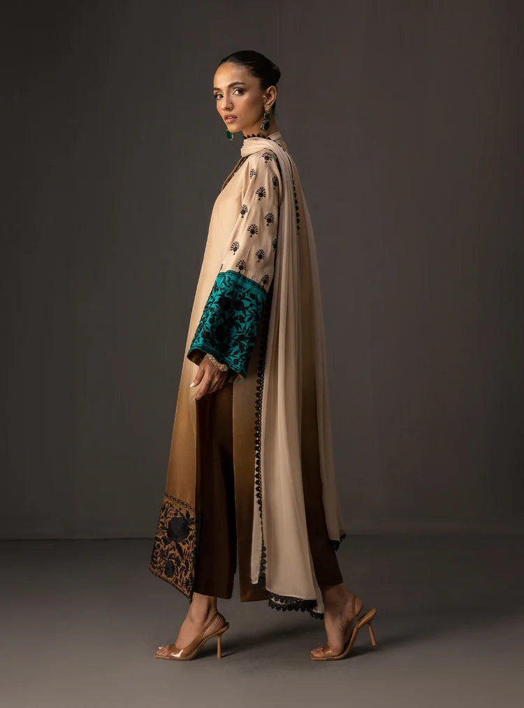 Woman wearing a long, patterned dress with a cape on a dark background