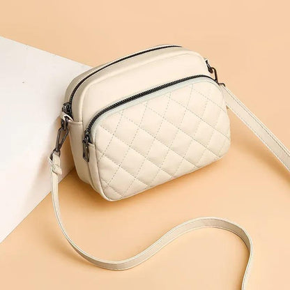 Quilted beige handbag with a strap on a beige background
