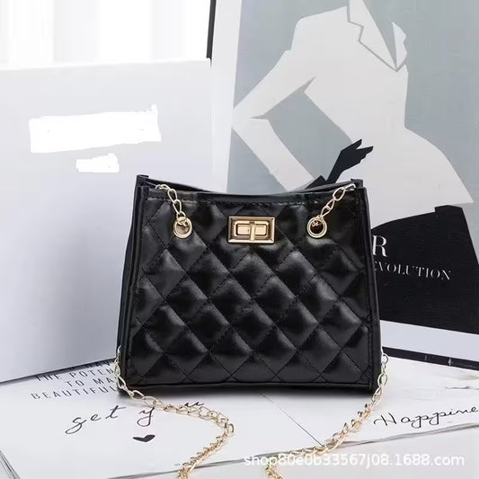 Black quilted handbag with gold chain on a magazine background