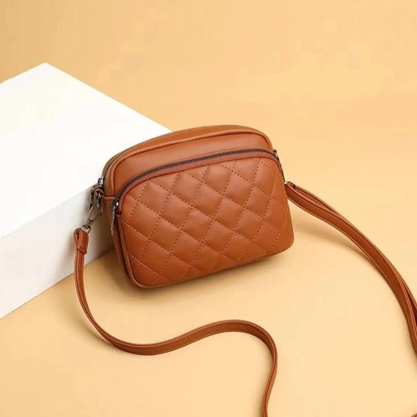 Brown quilted crossbody bag on a beige background