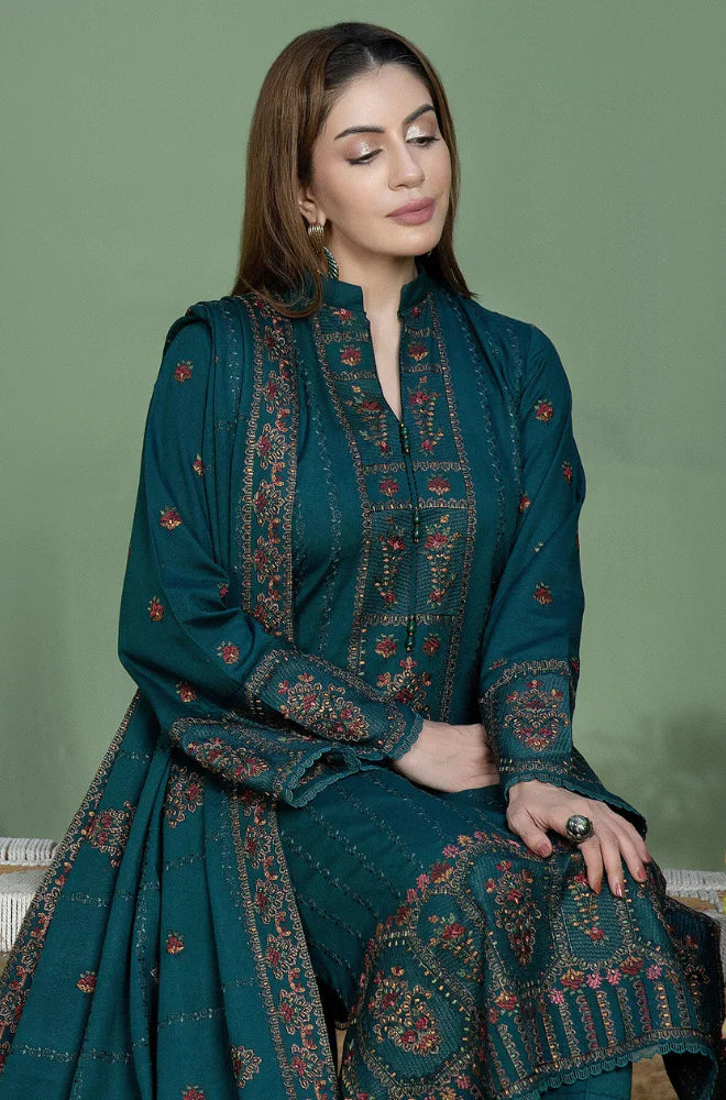 Woman wearing a teal embroidered traditional outfit against a green background