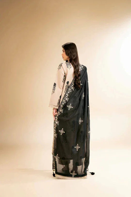 Woman wearing a black saree with silver patterns on a beige background