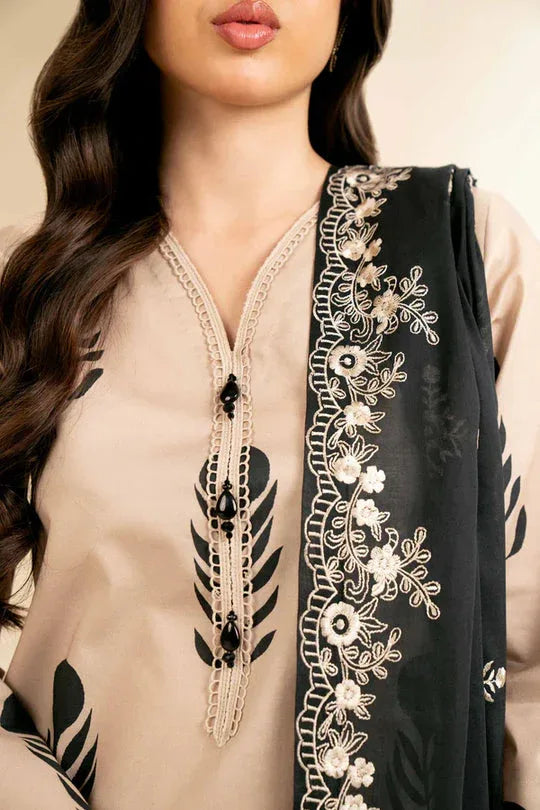 Close-up of a person wearing a beige and black embroidered outfit with a black scarf.
