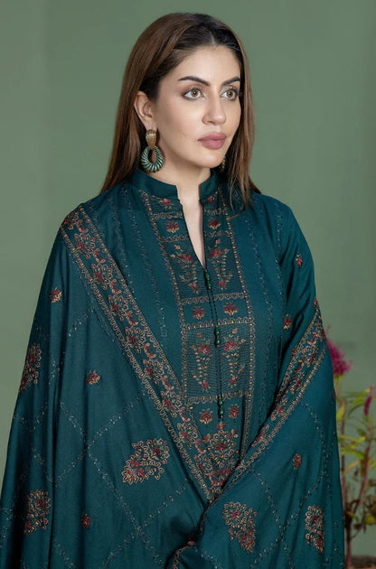 Woman wearing a teal embroidered traditional outfit against a green background