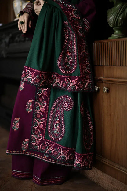 Person wearing a traditional outfit with intricate patterns in a dimly lit room.