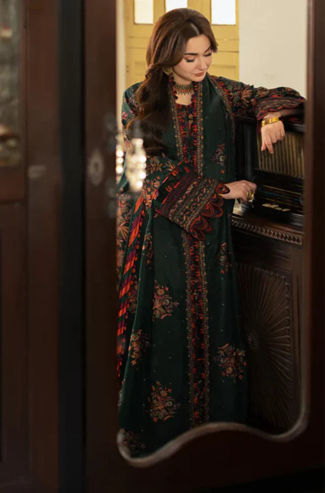 Woman in a dark green embroidered dress standing in front of a mirror.