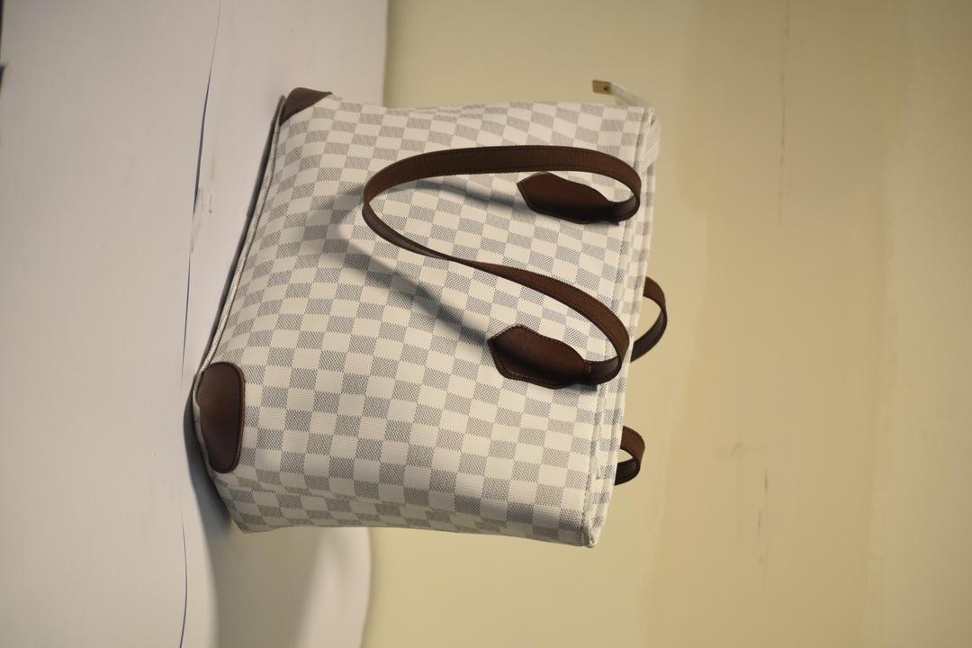 Checkered handbag with brown handles on a plain background