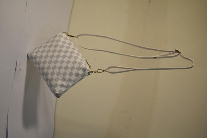 Checkered handbag with a strap on a plain background