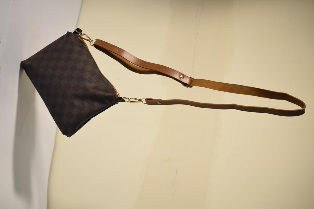 Brown leather handbag with a strap on a beige background