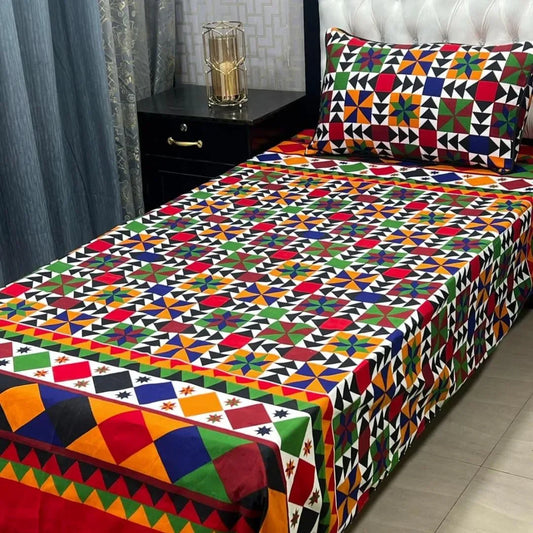 Colorful geometric patterned bedspread on a bed with a nightstand and decorative item in the background.