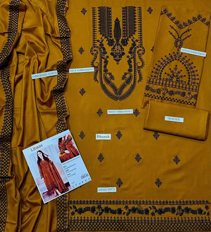 Mustard yellow fabric with black embroidery and a catalog on a matching fabric background