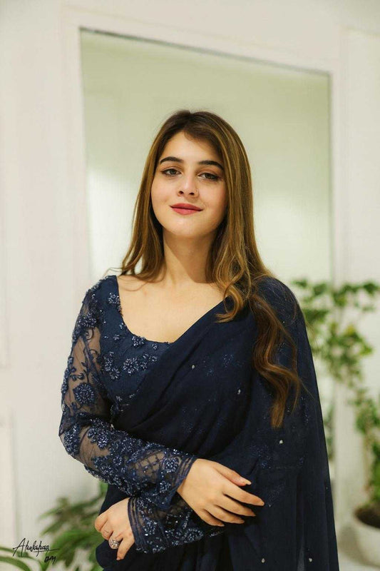 Woman wearing a dark blue saree with a blurred background