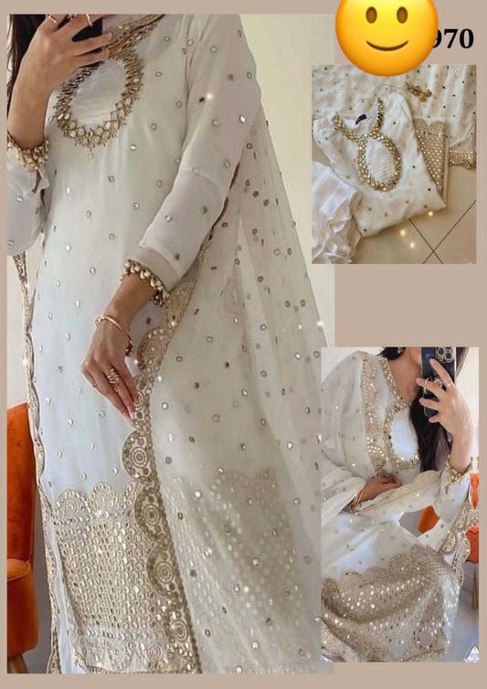 White embroidered outfit with gold details on a tiled floor.