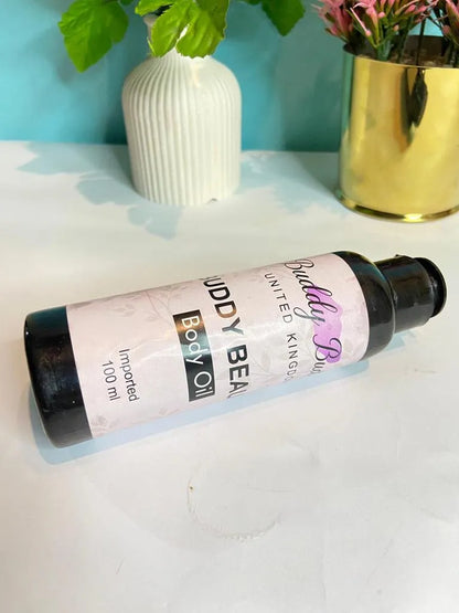 Buddy Beauty body oil bottle on a white surface with decorative vases in the background.