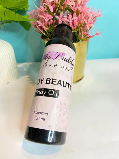 Body oil bottle with a pink label on a white surface with a blue background and pink flowers.