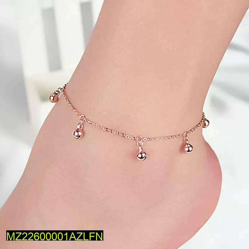 Rose gold anklet with dangling beads on a foot against a white background