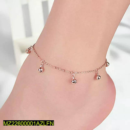 Rose gold anklet with dangling beads on a foot against a white background
