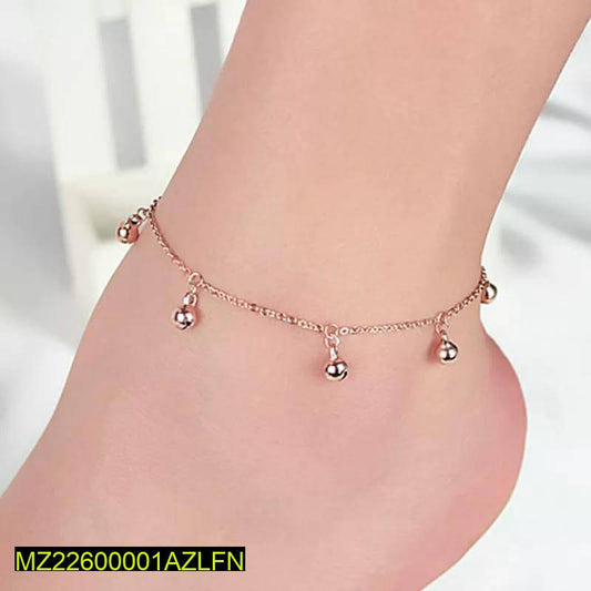 Rose gold anklet with dangling beads on a foot against a white background