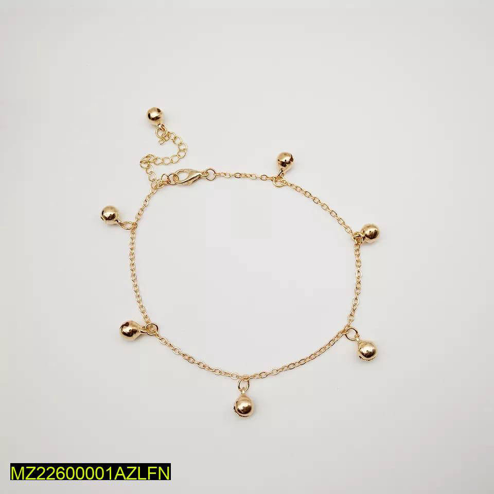 Gold anklet with small spherical charms on a light gray background