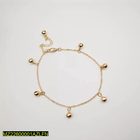 Gold anklet with small spherical charms on a light gray background